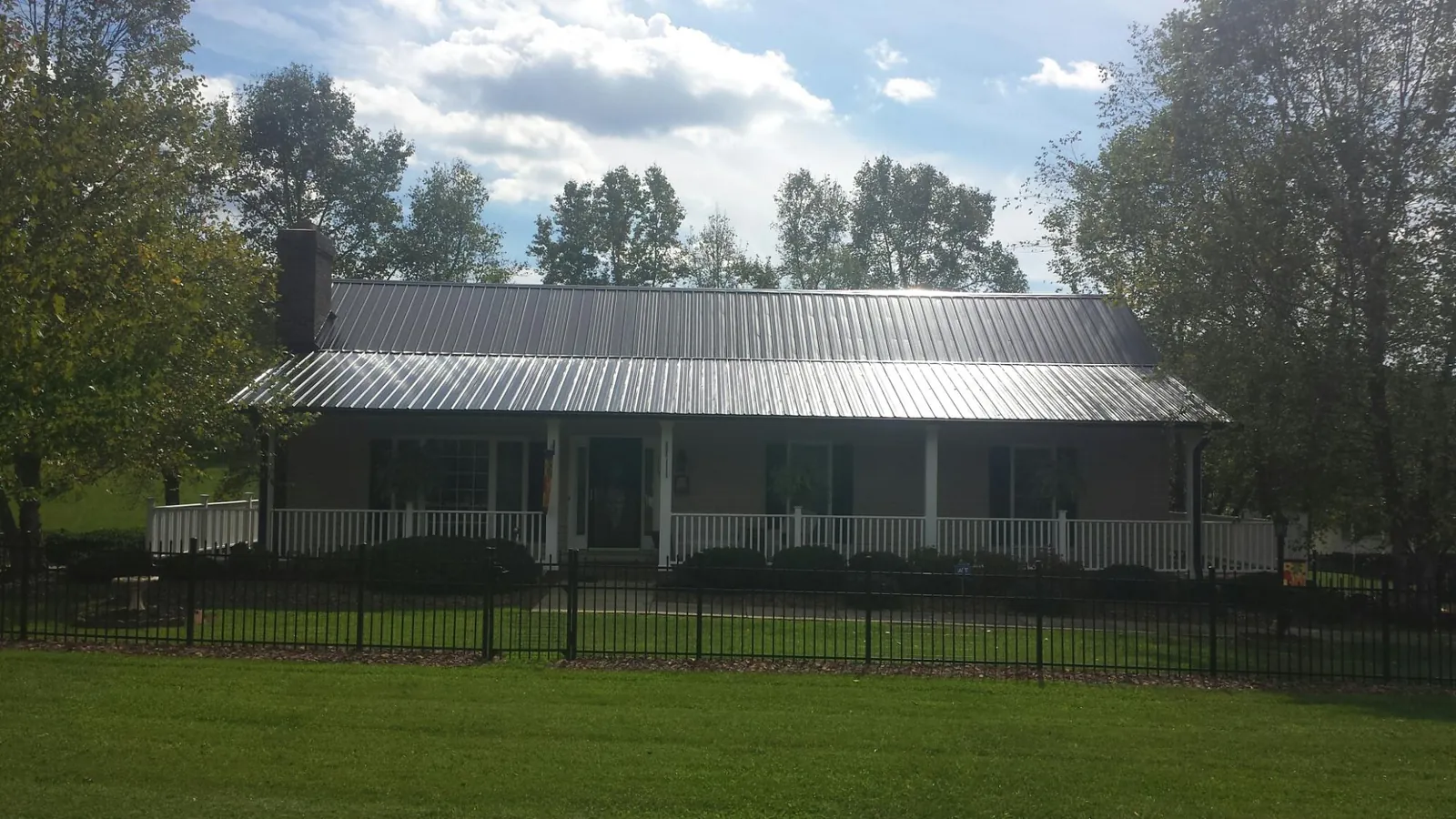 Gray metal roof on a brick ranch with a full width front porch — Gutter Guard Installation work by our crew in Middletown